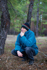 A rural guy posing in a pine forest in the autumn time.
