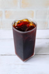 Top view of iced coffee in trasparent glass on white wooden background.