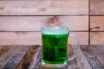 Single mug of green beer on wooden background