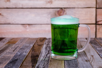 Single mug of green beer on wooden background