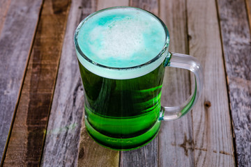 Single mug of green beer on wooden background