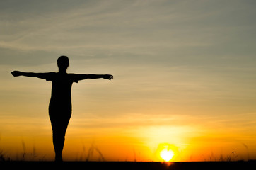 Fototapeta premium Woman silhouette is standing, raise one's hand for exercise, on evening .