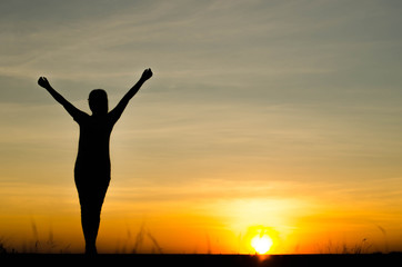 Fototapeta premium Woman silhouette is standing, raise one's hand for exercise, on evening .