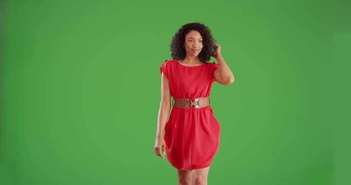 Fashionable black woman in red dress walking toward camera on green screen background. Stylish woman walks while laughing and smiling for greenscreen compositing on moving background plate. 4k
