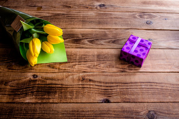 yellow tulips and gift on a wooden background