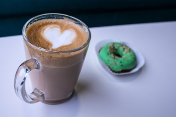 cup of coffee with a heart of foam and donut