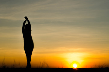 Woman silhouette is standing, raise one's hand for exercise, on evening .