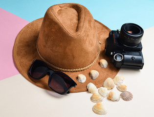 The concept of a resort on the beach. Felt hat, sunglasses, vintage film camera, seashells on a colored paper background..