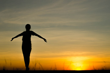 Woman silhouette is standing, raise one's hand for exercise, on evening .