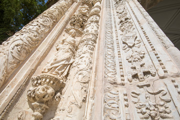 view from below of sculptures and art relief on exterior facade of ancient building of Museum Santa Cruz, landmark and monument of the Sixteenth century in Toledo city, Spain, Europe
