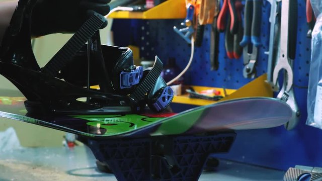 snowboarder fastens the mount to the snowboard. Prepares snowboard for winter to use