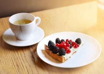 Photo of a macro of a cup of tea and a piece of cake with berries