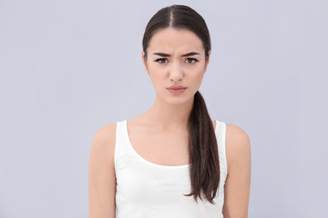 Young woman frowning her eyebrows on light background