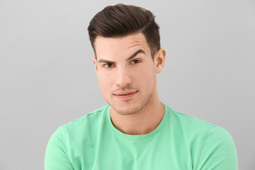 Young man with raised eyebrow on light background