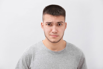 Emotional young man with dyed eyebrows on light background