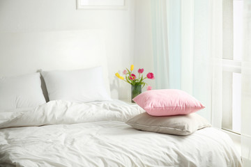 Fototapeta na wymiar Comfortable bed in light room interior