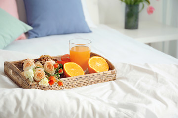 Tray with tasty breakfast on comfortable bed at home
