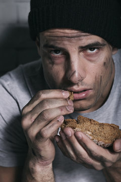 Homeless poor man eating piece of bread