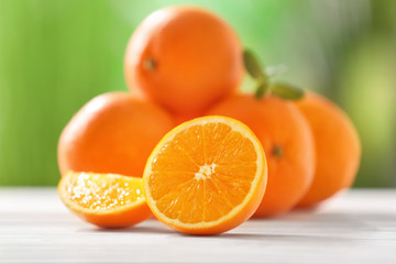 Juicy ripe oranges on table against blurred background