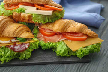 Tasty croissant sandwiches on table