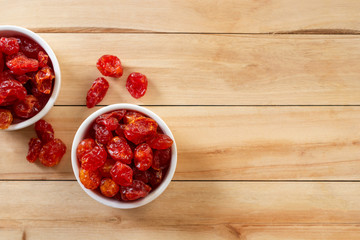 dried cherry tomatoes in white bowl on wooden background.