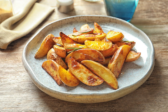 Plate with tasty potato wedges on table