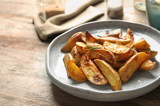Plate with tasty potato wedges on table
