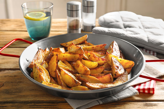 Dish with tasty potato wedges on table