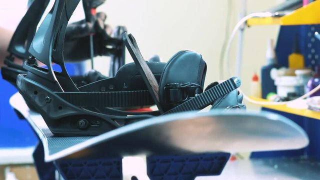 snowboarder fastens the mount to the snowboard. Prepares snowboard for winter to use