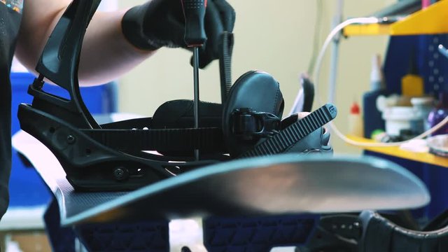 snowboarder fastens the mount to the snowboard. Prepares snowboard for winter to use