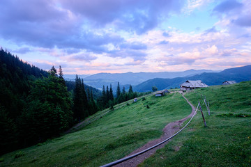 Beautiful mountains landscape with green meadow and wooden house. Carpathians, Ukraine.