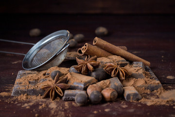 Chocolate, Spices, Spoon with Cocoa, Metal Strainer, Hazelnut on Dark Wooden Background. Copy space