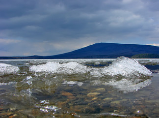 The ice on the Nizhnevoy reservoir against the background of the Kachkanar mountain. Kachkanar. Sverdlovsk region. Russia