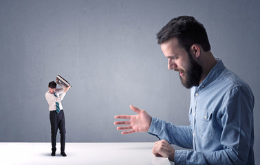 Young businessman fighting with miniature businessman