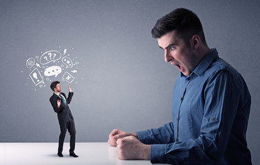 Young businessman fighting with miniature businessman