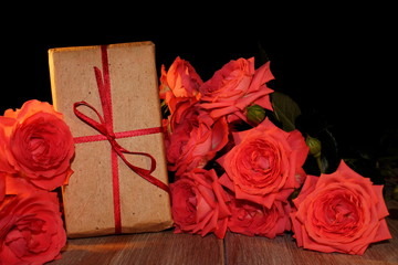  красивый подарок перевязанный красной лентой с красивыми розовыми розами       
