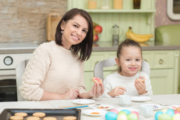 Obraz na płótnie Canvas Mom and her daughter baking together and decorating the cookies