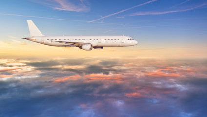 Fototapeta na wymiar Airplane jetliner flying above clouds in beautiful sunset light.