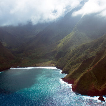 Aerial view of the coastline and foggy sea cliffs of Molokai, Hawaii, shot from a small, low-flying prop plane