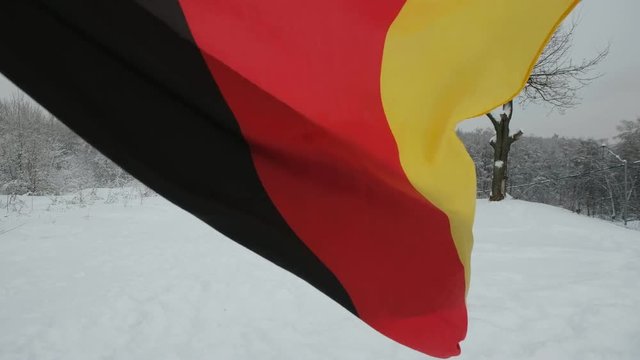 National flag of Germany waving in the wind with blurred mountains in the background