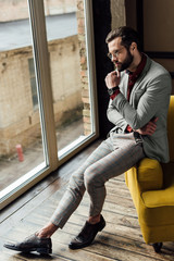 thoughtful man in trendy suit sitting at window