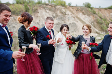 Fantastic wedding couple and bridesmaids with groomsmen drinking champagne in sand quarry.