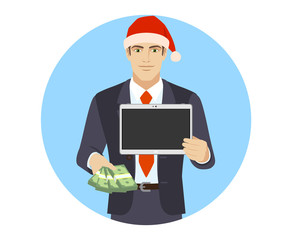 Businessman in Santa hat with money holding a digital tablet PC