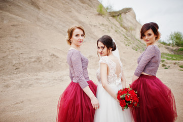 Bride posing with her bridesmaids in sand quarry on her wedding day.