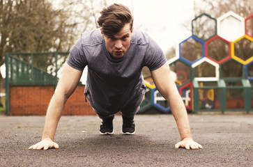 Man doing pushups exercise in the city park. Gym, fitness outdoor