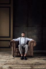 handsome stylish man thinking and sitting in armchair