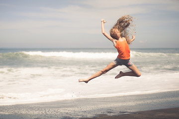 Fototapeta na wymiar teen girl jumping on the beach at blue sea shore