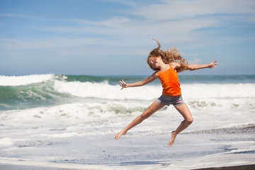 teen girl jumping on the beach at blue sea shore