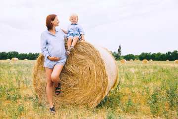 Pregnant woman and son on nature. Mother waiting of a second baby.