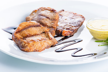 Grilled beef steak with sauce and greens on a white background